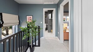 A hallway with a potted plant, a light fixture, and a door leading to a room with a bed and a lamp. - Paradykes House - Free Parking & Garden (Midlothian)