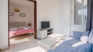 Ett modernt hotellrum med en säng, en TV, en soffa och ett litet bord.