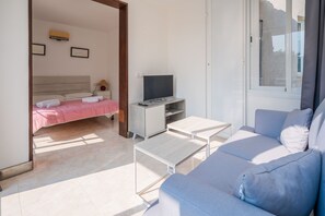 A modern hotel room with a bed, a TV, a sofa, and a desk. - Ferrer , villa near the beach (Alcúdia)