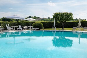 A swimming pool with lounge chairs and umbrellas, surrounded by a hedge and trees. - Villa Zanina Sonia Apartment (Peschiera del Garda)