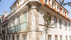 Ein historisches Gebäude mit einem Ziegeldach, einem Balkon mit Eisenengelgitter und einer Kopfsteinpflasterstraße.