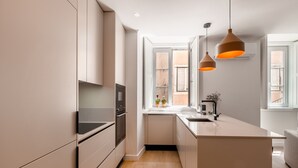 Eine moderne Küche mit einer zentralen Kochinsel, Pendelleuchten und Blick durch das Fenster.