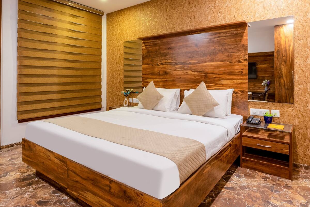 Ein Schlafzimmer mit Holzbettgestell, Deckenventilator, Holz-Kopfteil, Nachttisch und Marmorboden.