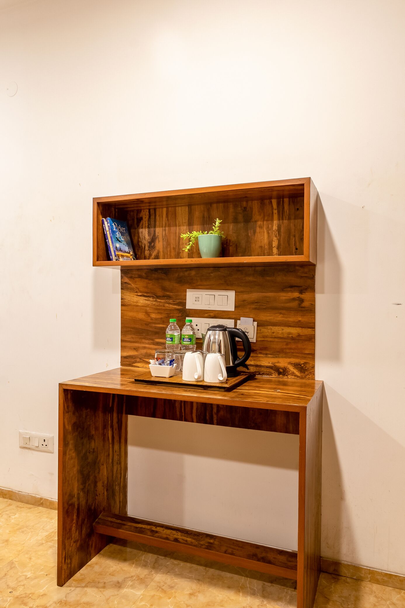 Un bureau en bois avec une étagère, une bouilloire, des bouteilles et un livre.