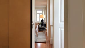 Ein Flur mit einer Holztür, einem schwarz-weißen Streifen Teppich und einer Lampe auf einem Tisch.