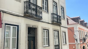 Ein mehrstöckiges Gebäude mit weißer Fassade, schwarzen Fensterrahmen und aufwendigen schwarzen Balkonen.
