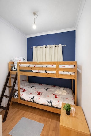 A bunk bed with a ladder, a small table with a plant, and a curtain. - Spacious Easter Road 2BR Apartment (Edinburgh)