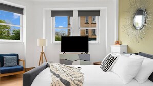 Une chambre à coucher moderne avec un lit, une télévision, un bureau et une chaise.