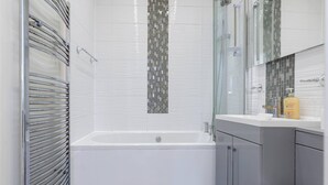 Une salle de bain moderne avec une baignoire blanche, des meubles gris et une cabine de douche en verre.