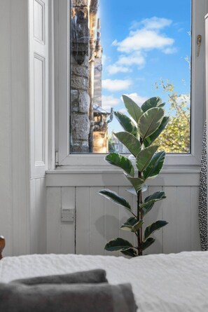 A room with a window, a plant, and a bed. - Bright 2 Bedroom Flat on Leith Walk (Edinburgh)