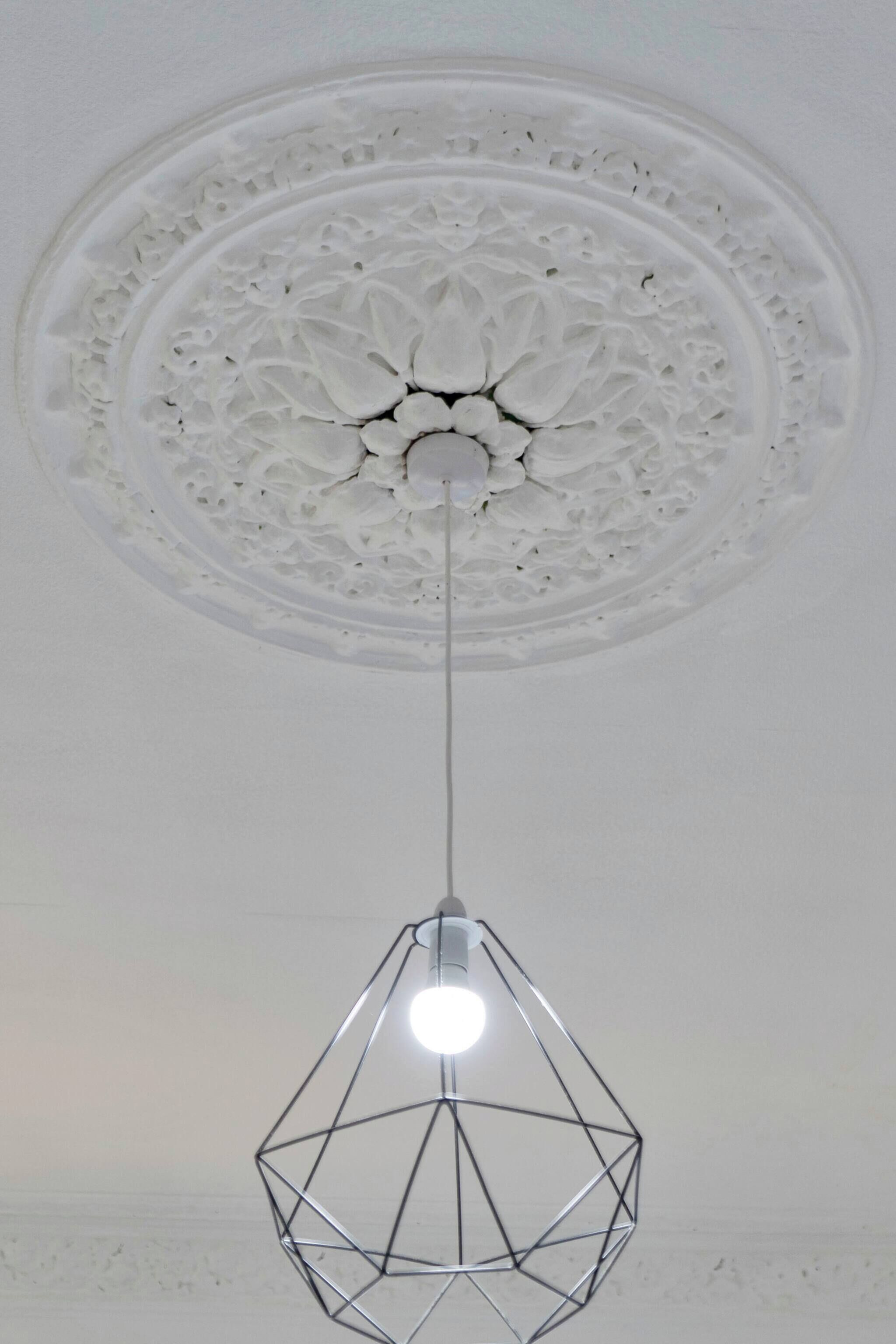 A geometric pendant light hanging from a ceiling with an ornate, circular design.