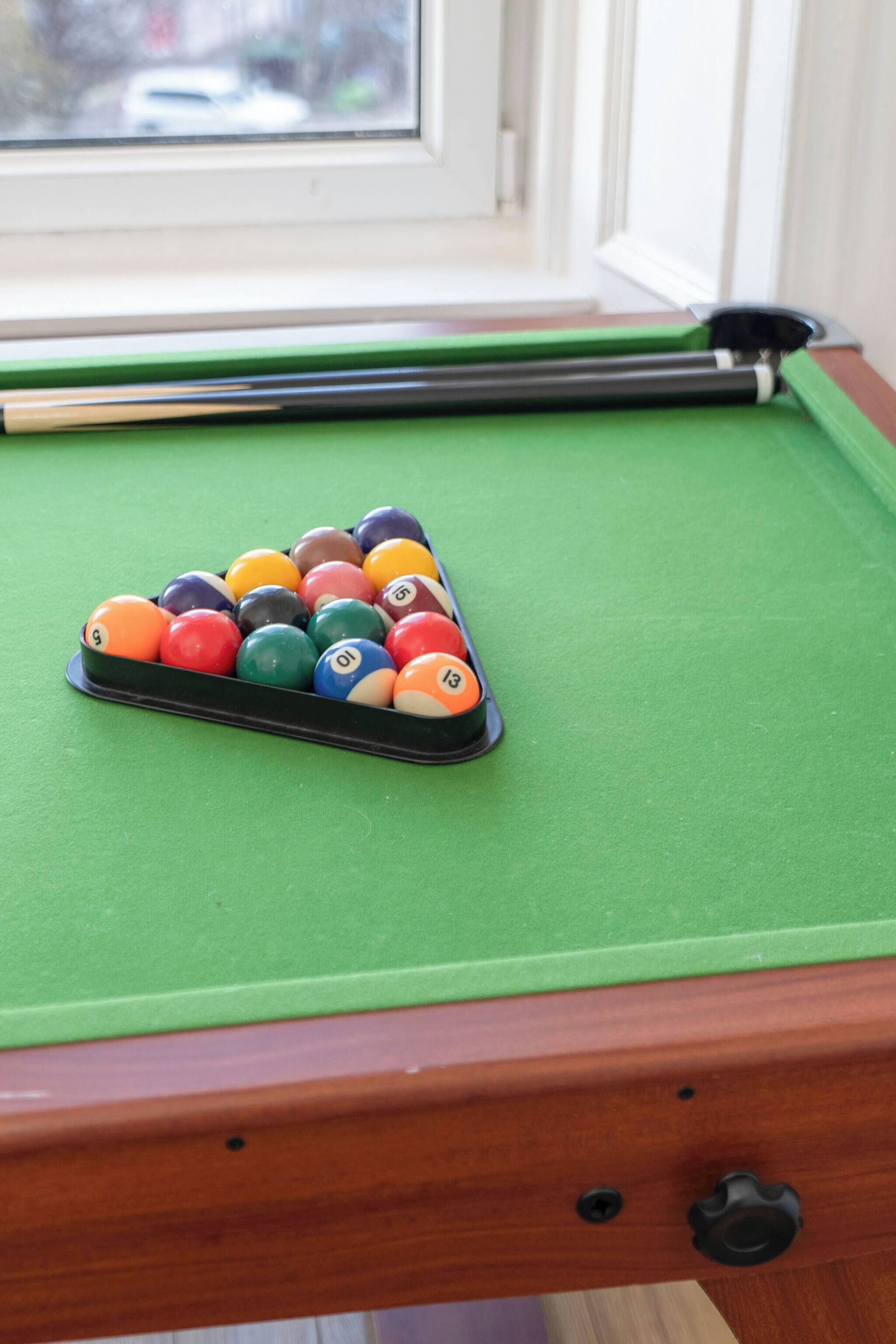 A pool table with a green felt surface and a set of numbered balls.