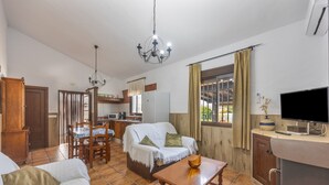 Een woonkamer met een bank, een eettafel, een televisie en een keukenhoek.