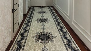 A hallway with a patterned carpet, white walls, and a door on the left.