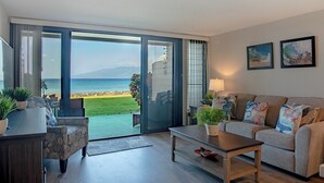 Un salon moderne avec vue sur la mer, comprenant un ensemble de canapés, une table basse et un coin repas.