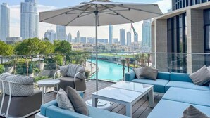 Une terrasse sur le toit avec des sièges en plein air, une piscine et une vue panoramique sur la ville.