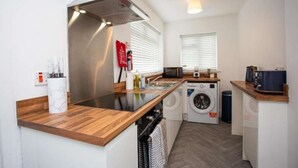Eine kompakte Küche mit Einbauofen, Mikrowelle und Waschmaschine, Holz Arbeitsplatten und einem kleinen Spülbecken.