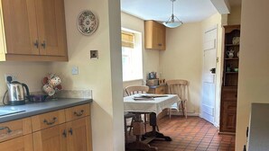 Una cocina con armarios de madera, piso de baldosas y un comedor con mesa y sillas.