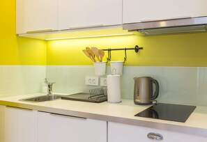 A modern kitchen with a sink, stove, and utensils hanging on a rack. - Prime City Centre Location: MirÓ Studio Apartments Zagreb (Zagreb)