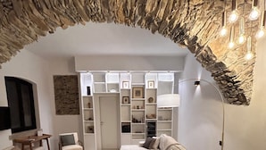 A modern living room with a stone archway, a sofa, armchairs, a coffee table, and a lamp. - Villa Olive Mill Terra Rossa  (Corniglia)