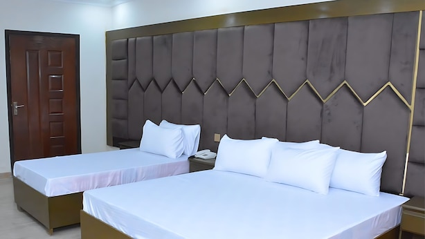 Une chambre d’hôtel avec deux lits simples, une porte en bois et une tête de lit rembourrée.