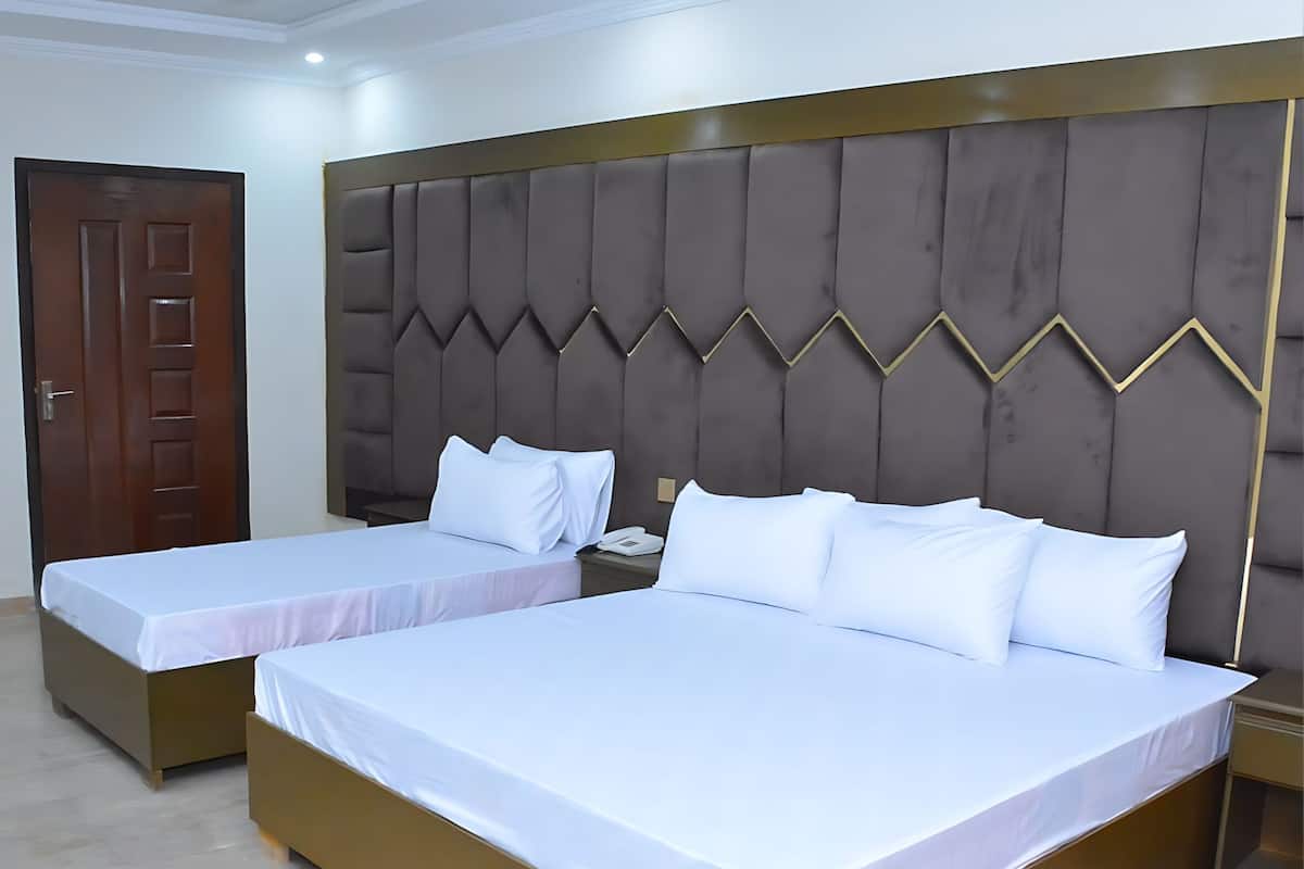 Een hotelkamer met twee enkele bedden, een houten deur en een bekleed hoofdeinde.