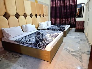 A hotel room with two beds, a large mirror, and a chair. - New Maharaja Hotel (Rawalpindi)