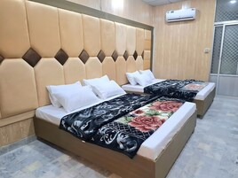 Ein Hotelzimmer mit zwei Betten, jeweils mit Kopfteil und weißer Bettwäsche.