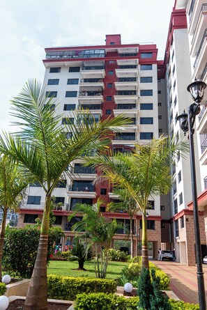 A multi-story residential building with balconies, surrounded by well-maintained gardens and palm trees. - State House Haven 3 Bedroom Suite (Nairobi)