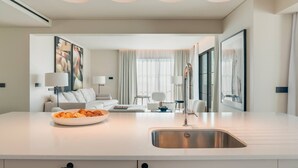 Una cocina moderna con una isla grande, pileta de acero inoxidable e iluminación colgante.