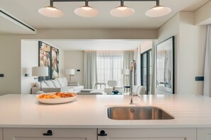 A modern kitchen with a large island, stainless steel sink, and overhead lighting. - Villa Mangoni - Brand New Luxury Villa (Funchal)