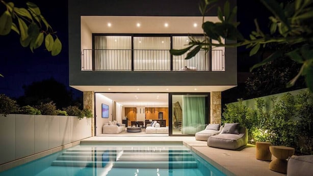 Una casa moderna de dos pisos con piscina, balcón e interior luminoso.