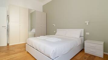 Ein Schlafzimmer mit Bett, Nachttisch, Kleiderschrank und Spiegel.