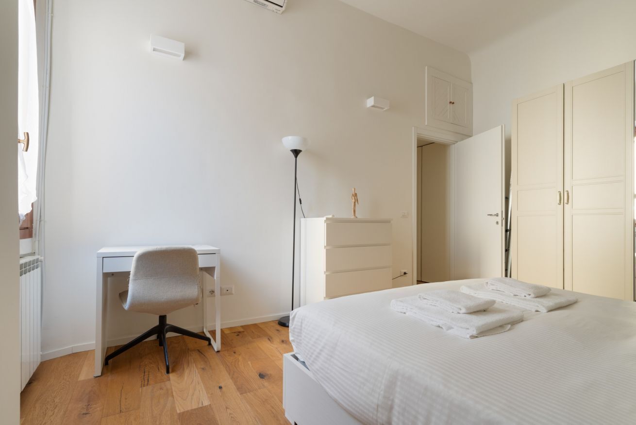 A bedroom with a bed, a desk, a chair, a dresser, and a wardrobe.