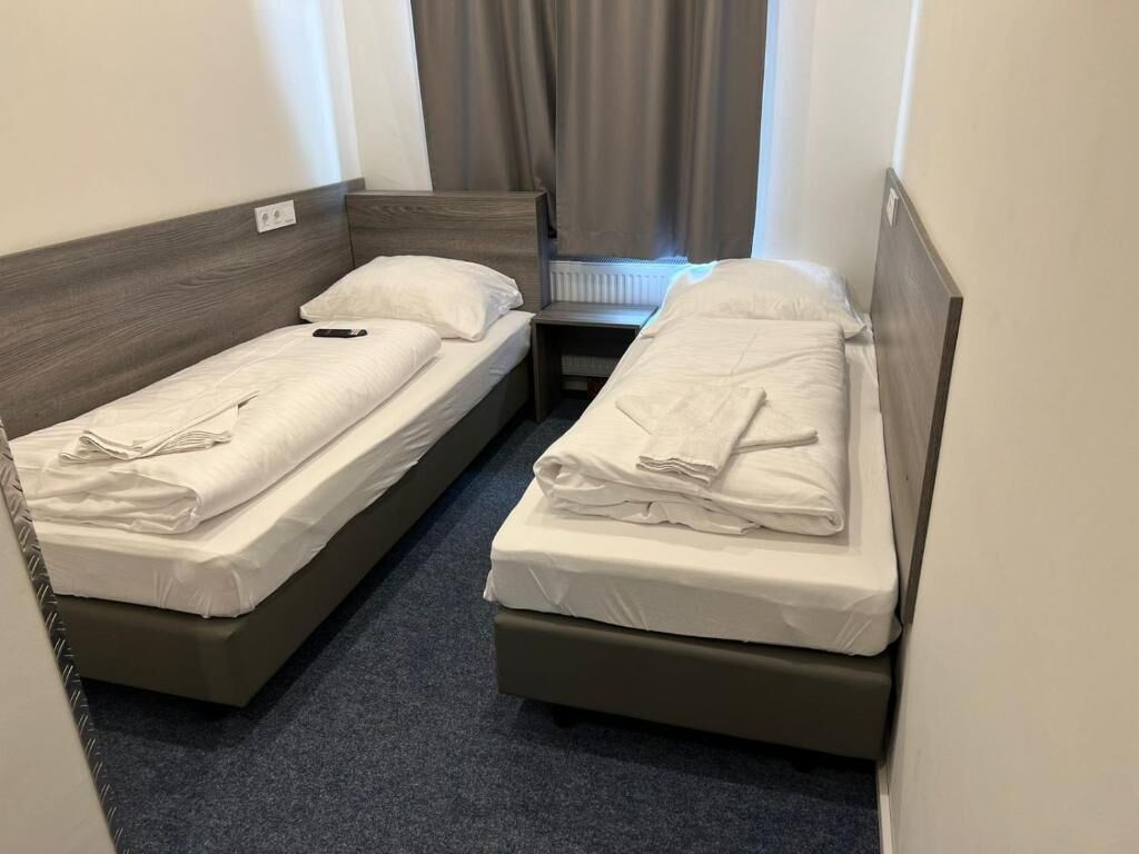 Una habitación pequeña con dos camas individuales, cada una con cabecero de madera y ropa de cama blanca.