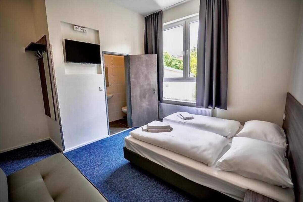 Een hotelkamer met een bed, een bank, een televisie en een badkamer zichtbaar door een open deur.
