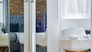 Een kamer met een spiegelkast, een bakstenen muur, een bank, een witte stoel en een radiator.