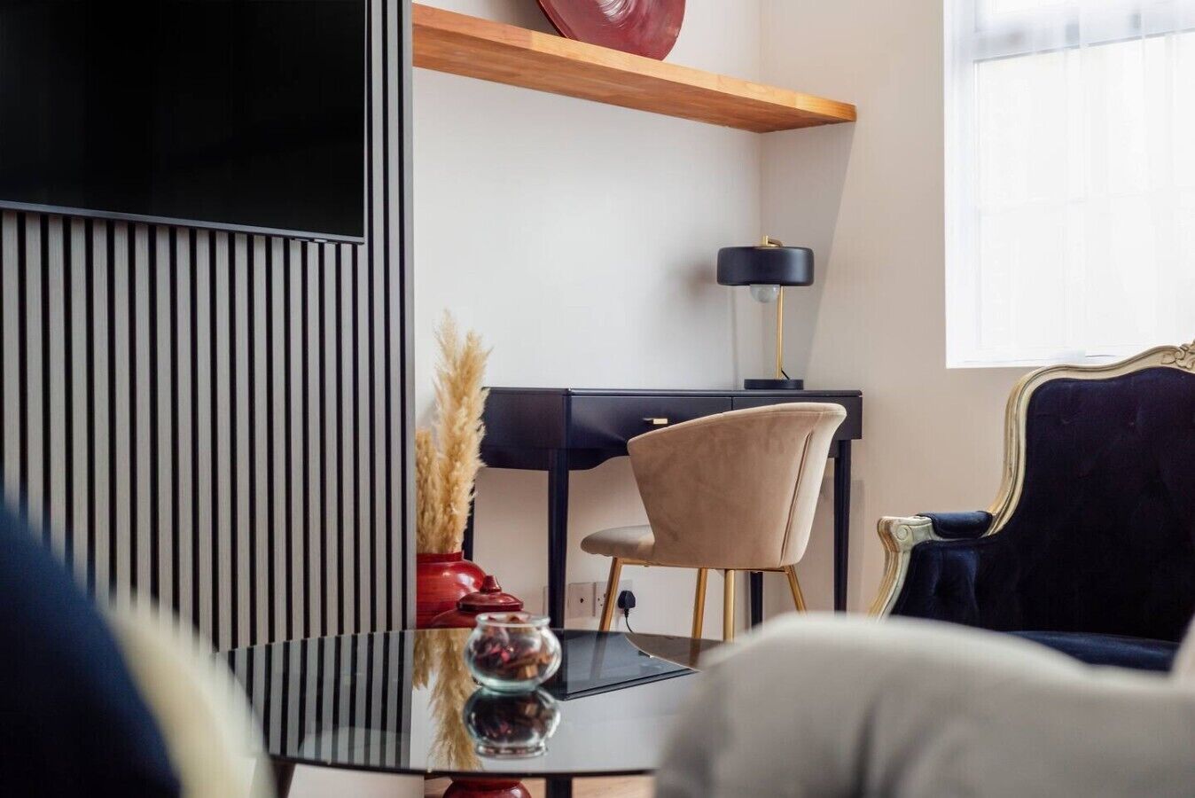 Ein modernes Wohnzimmer mit Fernseher, Schreibtisch, Sessel und Sofa.