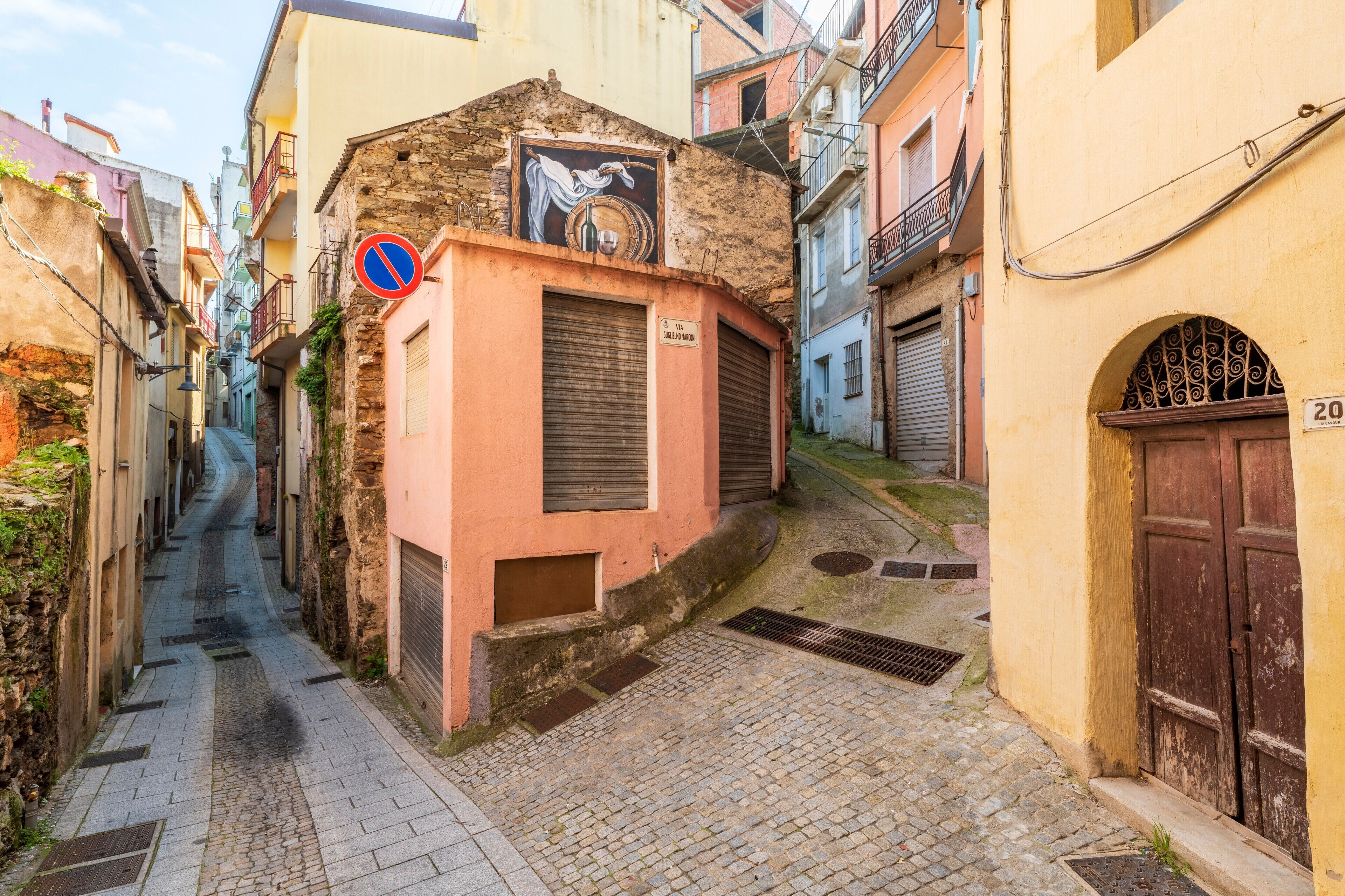 A narrow street with buildings on either side, a no parking sign, and a door with the number 20.