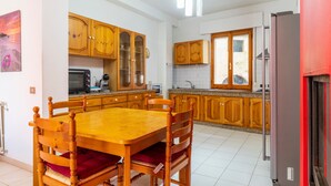A kitchen with wooden cabinets, a dining table with chairs, a refrigerator, and a window.