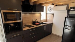 A modern kitchen with a built-in oven, microwave, and black refrigerator. - House in Vias-plage Near Sandy Beach (Vias)