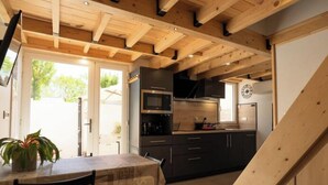A modern kitchen with wooden beams, a dining area, and a view of the outdoors. - House in Vias-plage Near Sandy Beach (Vias)