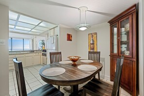A dining area with a wooden table, four chairs, a central decorative bowl, and a ceiling light. - Bi-level, direct oceanfront retreat with bayviews and indoor pool (Ocean City)
