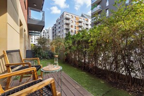 Ein Balkon mit Gartenmöbeln, einem kleinen Tisch und einem Blumentopf.