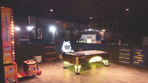 A billiards table with neon lights, a vending machine, and a truck labeled "Rashad" in a dimly lit indoor setting. - Vishram Executive Rooms (Vasai)
