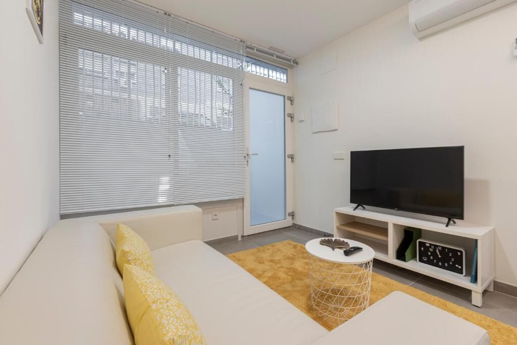 Ein modernes Wohnzimmer mit einer Couch, einem Fernseher und einem kleinen Beistelltisch.