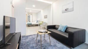 Ein modernes Wohnzimmer mit einem Flachbildfernseher, einem schwarzen Ledersofa, einem Couchtisch und einem blauen Teppich.