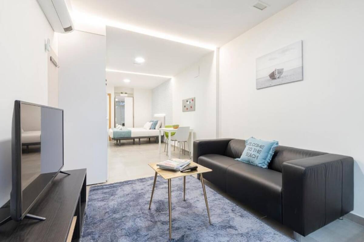 Een moderne woonkamer met een flatscreen televisie, een zwarte leren bank, een salontafel en een blauw vloerkleed.