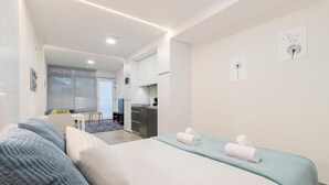 Ein modernes Hotelzimmer mit einem Bett, einem Schreibtisch und einer Küchenzeile.
