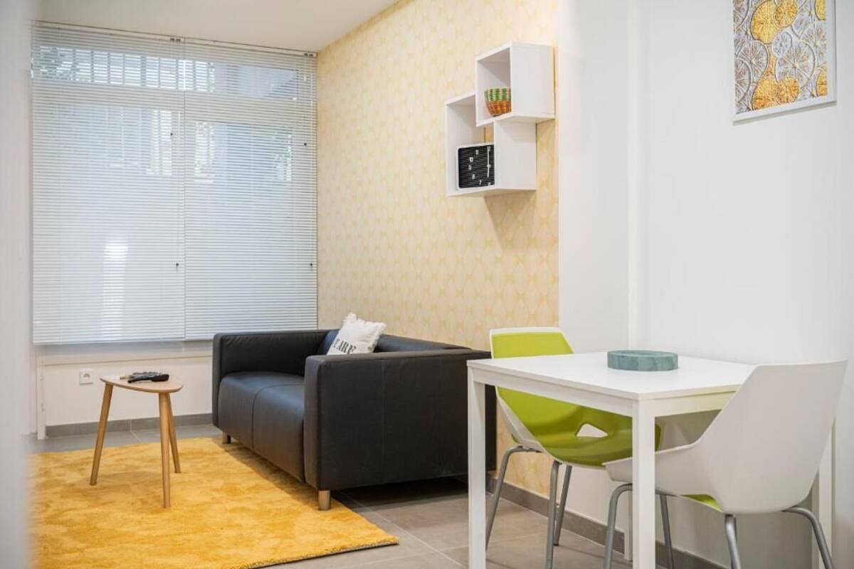 Een moderne woonkamer met een bank, een kleine tafel, en een eethoek met stoelen.